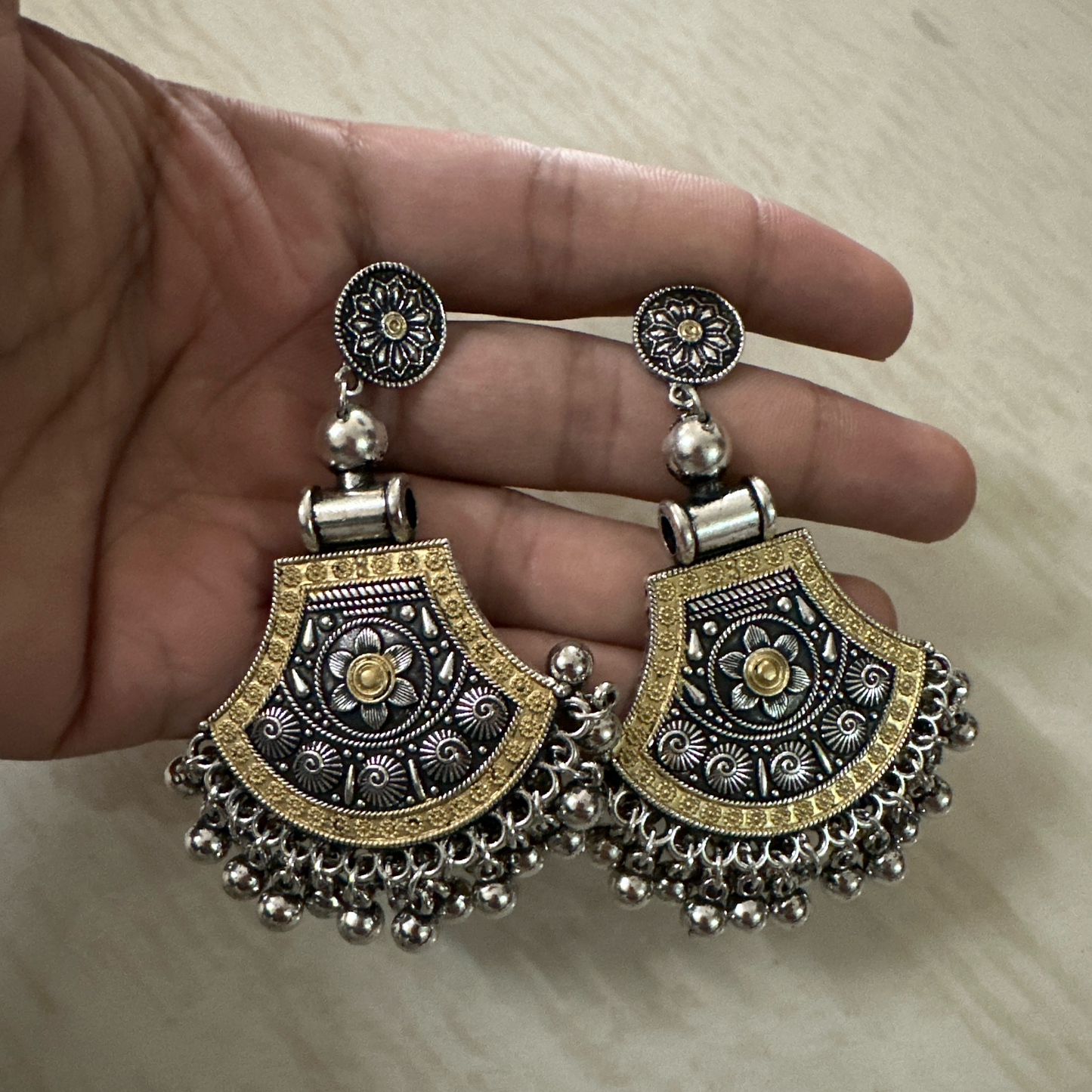Oxidised silver earrings with floral design, golden detailing, and hanging ghungroos.
