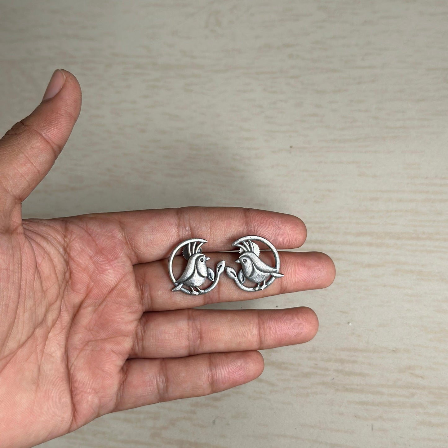 Oxidized stud earrings featuring a cute bird design in a circular frame.