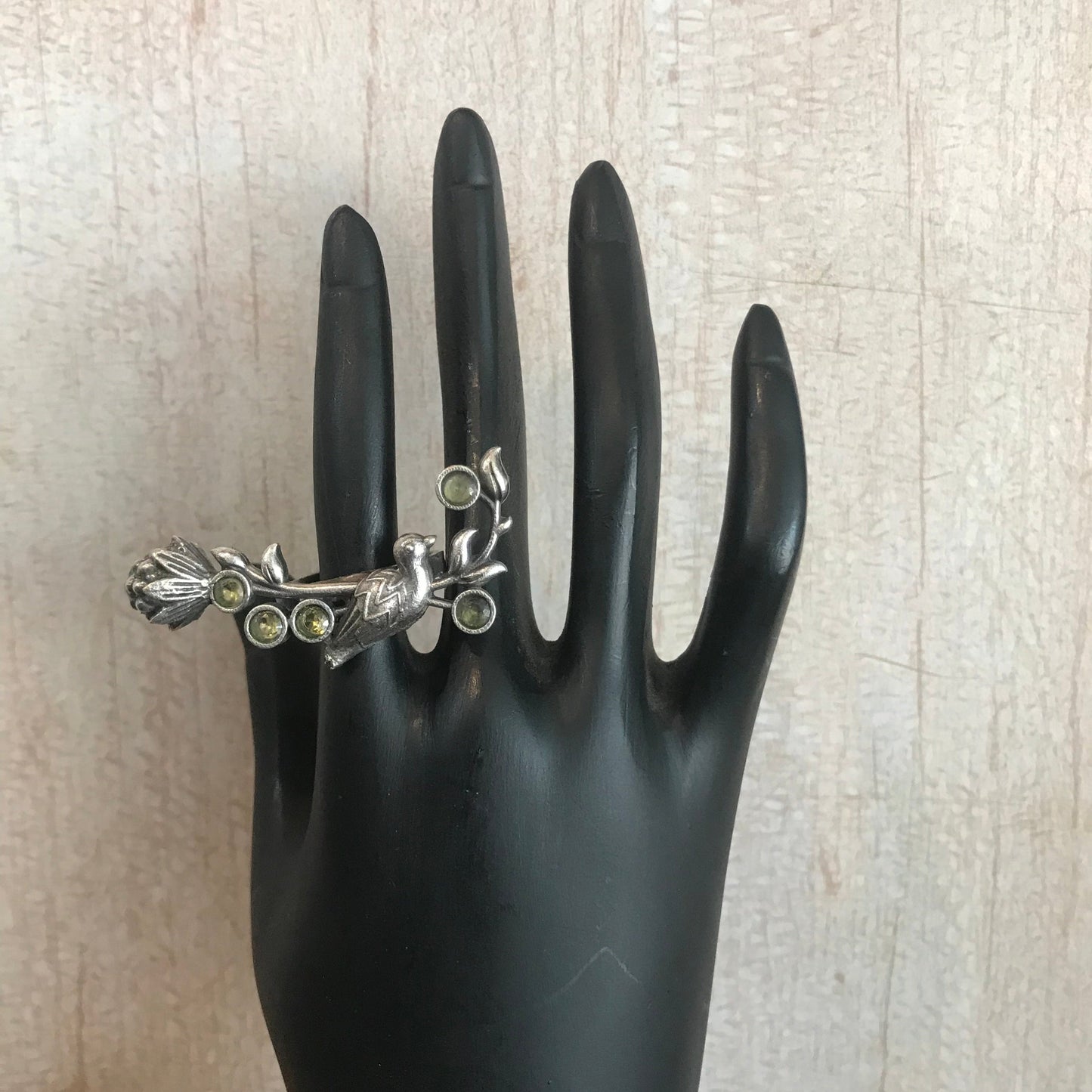 oxidized silver ring features a leafy vine design with green stone accents