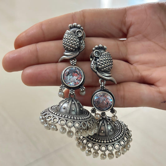 Oxidized silver jhumka earrings with parrot motif, sparkling stone, and pearl accents.