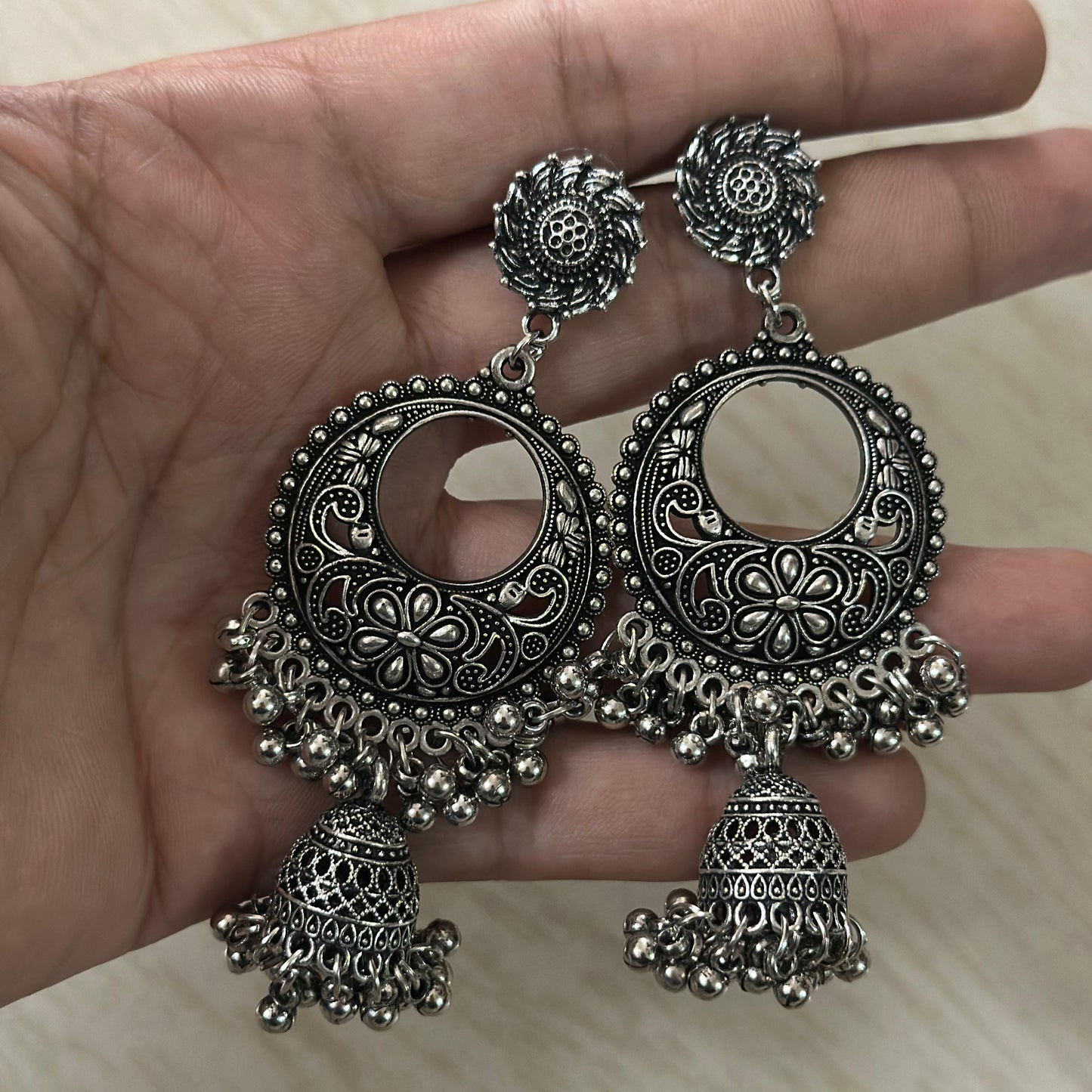 oxidized silver earrings with floral motifs, circular cut-outs, and traditional jhumka drops