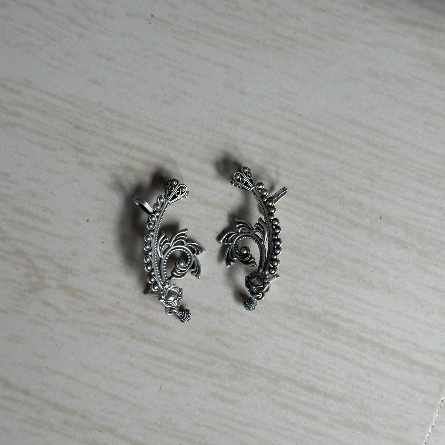 Oxidized ear cuffs with intricate floral and swirl detailing.