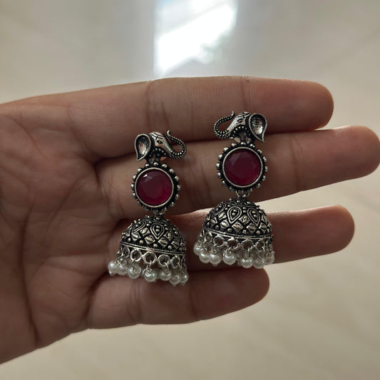 oxidized silver jhumka earrings with red stones and pearl accents, featuring intricate elephant design.
