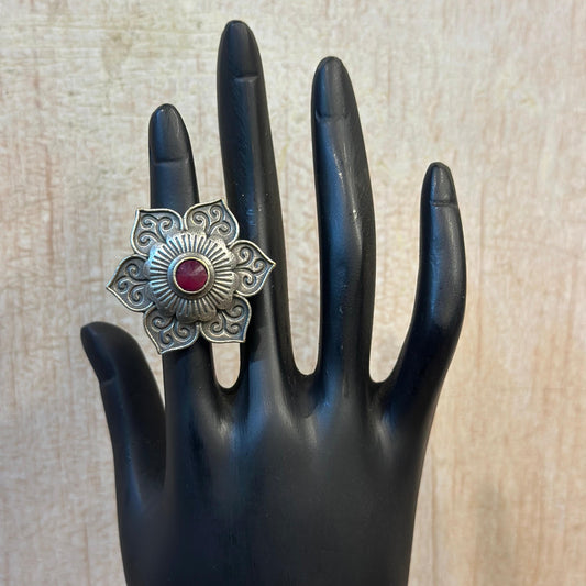 Oxidised silver floral ring with intricate design and red stone centerpiece.