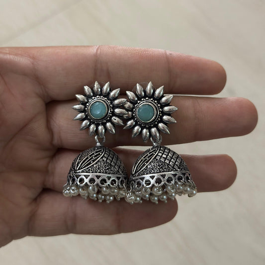 Oxidized silver jhumka earrings with sunflower studs, turquoise center, and pearl hangings.