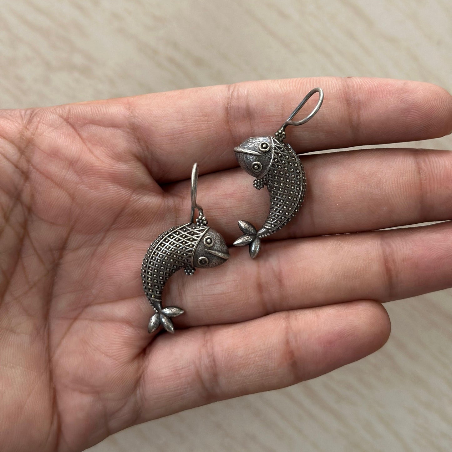 Oxidized silver fish-shaped earrings with intricate detailing.