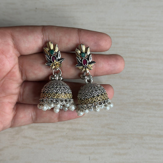 Oxidized silver jhumkas with floral tops, gold accents, and pearl hangings.