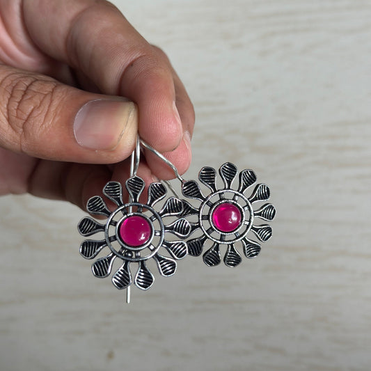 Oxidized silver floral earrings with petal-like detailing and a bold pink center stone.